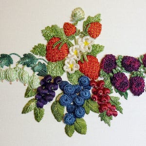 May include: Embroidered design featuring strawberries, blackberries, and gooseberries. The strawberries are red with green leaves, the blackberries are purple, and the gooseberries are green. The design is stitched on a white fabric.