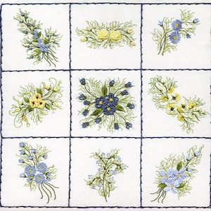 May include: Nine embroidered floral designs on a white fabric background. The designs are arranged in a grid pattern and feature blue, yellow, and green flowers.