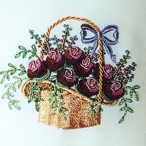 May include: Embroidered image of a basket overflowing with dark red roses, green leaves, and small purple berries. The basket has a woven texture and a twisted handle. A purple bow is tied to the handle.