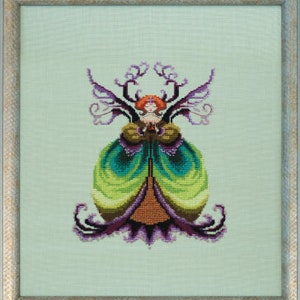 May include: A cross-stitch embroidery of a fairy with purple wings and a green, blue, and brown dress. The fairy is surrounded by a leafy, vine-like design.