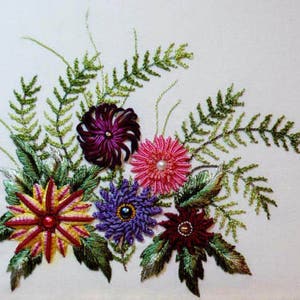 May include: Embroidered floral design featuring five flowers in shades of pink, purple, red, and yellow. The flowers are surrounded by green fern-like leaves.