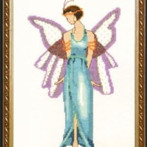 May include: A cross-stitch embroidery of a woman with butterfly wings. She is wearing a blue dress with orange accents and a feathered headpiece. The background is white.