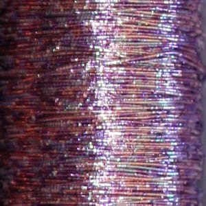 May include: A spool of iridescent purple and silver metallic thread. The thread is wound tightly and has a shiny, reflective finish.