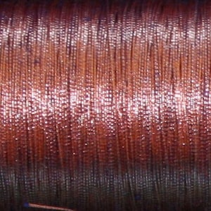 May include: Close-up of a spool of copper wire, wound tightly and showing a reddish-brown color with a slight sheen.
