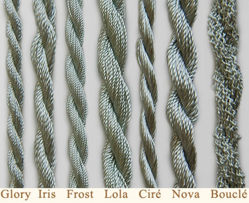 May include: Close-up of eight different types of silver-grey embroidery floss, including Glory, Iris, Frost, Lola, Cir&eacute;, Nova, and Boucl&eacute;.