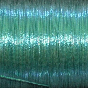 May include: A spool of teal iridescent thread. The thread is wound tightly and has a subtle shimmer.