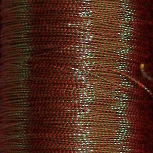 May include: Close-up of a spool of red and green metallic thread. The thread has a shiny, iridescent finish.
