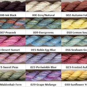 Peut inclure: Un nuancier de fils à tricoter de différentes couleurs, dont blanc, noir, marron, bleu, rose, vert et jaune. Chaque couleur est étiquetée avec un numéro et un nom, comme "Snow Drift White" et "Ink Black."