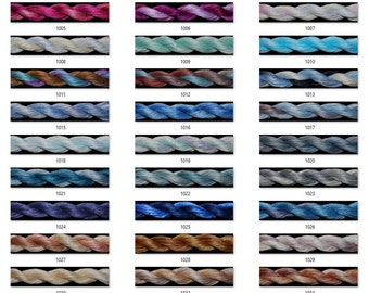 May include: A collection of 36 embroidery floss skeins in various shades of blue, purple, pink, brown, and grey. Each skein is labeled with a number from 1002 to 1036.