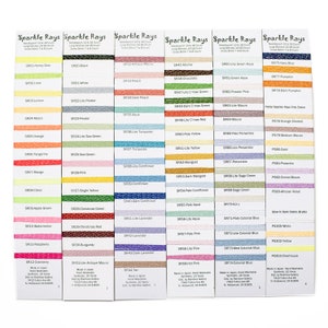 May include: A color chart of embroidery floss with a variety of colors, including red, blue, green, yellow, orange, purple, pink, brown, and black. The chart is labeled "Sparkle Rays" and includes the floss number and color name for each color. The floss is made in Japan and is hand washable.