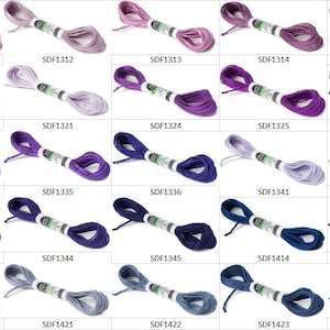 May include: A collection of twenty-five skeins of embroidery floss arranged in a grid, each featuring a unique shade of purple or blue. Every skein is wrapped with a white paper label displaying a specific product code, such as SDF1311 through SDF1424.