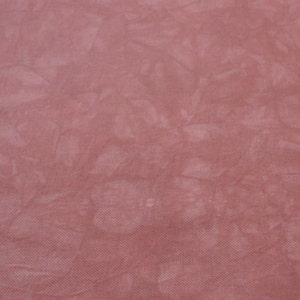 May include: A close-up of a soft, pink fabric with a subtle tie-dye pattern. The fabric has a slightly textured surface.