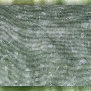 May include: A green and white textured fabric with a subtle pattern. The fabric has a slightly metallic sheen and is framed by a green border.