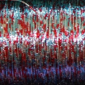 May include: Close-up of a spool of metallic thread with alternating red, blue, and silver strands.