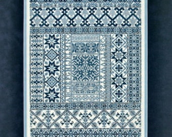 May include: A blue and white sampler with a variety of geometric patterns. The sampler is framed in a white frame with a blue mat.