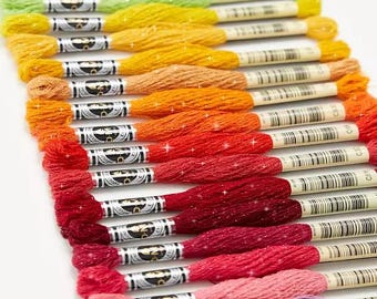 May include: A rainbow assortment of embroidery floss spools with glitter thread. The spools are labeled with DMC numbers and arranged in a gradient from green to purple.