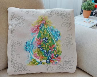 Könnte beinhalten: Ein quadratisches beiges Zierkissen mit einem zentralen Kreuzstichmotiv in Tropfenform, gefüllt mit Blaubeeren, grünen Blättern und zwei blauen Schmetterlingen. Der umgebende Bereich zeigt eine hellgraue Kontur von Blaubeerzweigen.
