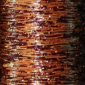 May include: Close-up of a spool of metallic thread with a mix of copper and gold colors. The thread is shiny and has a slight shimmer.