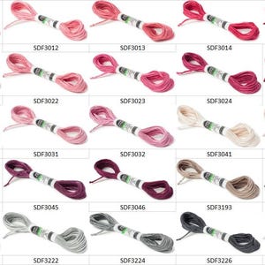 May include: A grid of twenty-five skeins of embroidery floss in various shades of pink, red, purple, brown, gray, and white. Each skein is wrapped with a white paper label featuring the product code, such as SDF3011 through SDF3311.