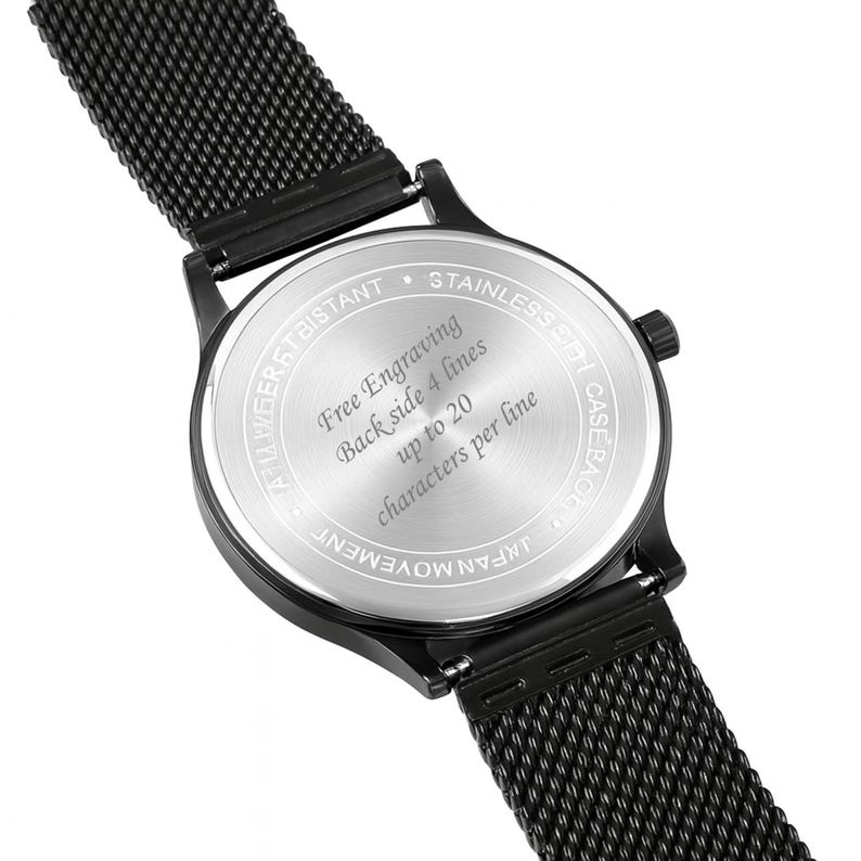 May include: Close-up of a black wristwatch with a mesh band. The watch's back features text indicating free engraving with up to 20 characters per line, across 4 lines. The watch is water resistant and has a stainless steel case.