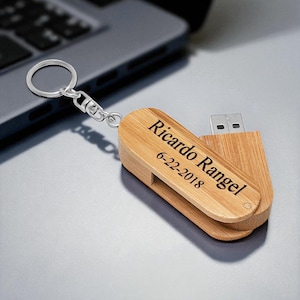 May include: A wooden USB flash drive with a silver keyring. The drive is engraved with the name "Ricardo Rangel" and the date "6-22-2018". The USB drive is made of light-colored wood.