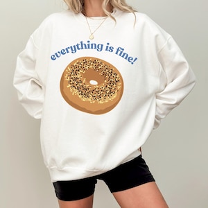 May include: White sweatshirt with a graphic of a bagel and the text "everything is fine!" in blue.