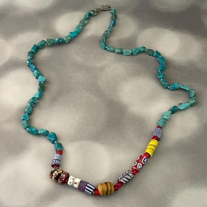 May include: A turquoise stone necklace with a variety of colorful beads, including red, yellow, blue, and white.