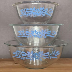 May include: Set of three glass mixing bowls with a blue floral design. The bowls are nested inside each other.