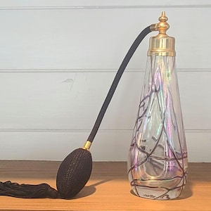 May include: A vintage glass perfume atomizer with a black and gold spray nozzle and a clear glass bottle with a black and iridescent design.