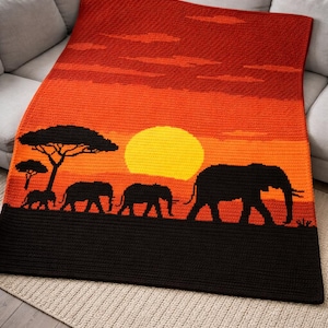 May include: A crocheted blanket depicting a sunset scene with elephants. The blanket uses orange and yellow gradients, with black silhouettes of elephants and trees. The blanket is displayed on a gray sofa, creating a warm, inviting aesthetic.