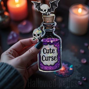 May include: A holographic sticker of a purple potion bottle with a skull and bat on top. The bottle has a label that says "Cute Curse".