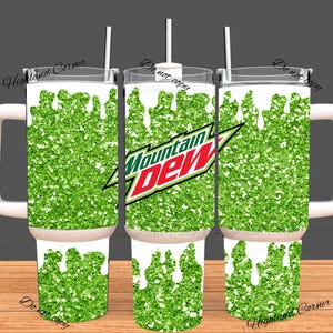 Puede incluir: Un juego de tres vasos aislados con asas y tapas blancas. Los vasos presentan un diseño de purpurina verde con gotas blancas y el logotipo de Mountain Dew. Cada vaso tiene una pajita blanca.
