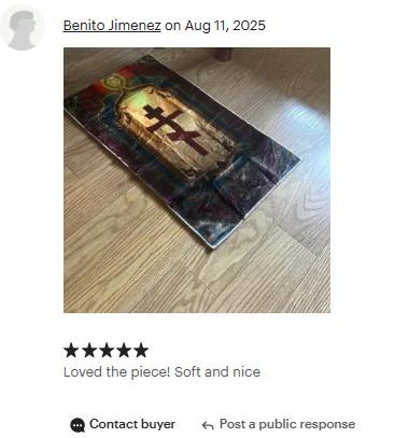 May include: A rectangular, religious-themed artwork featuring a central cross design. The artwork has a gold and brown color scheme with a dark border. The image is on a wooden floor.