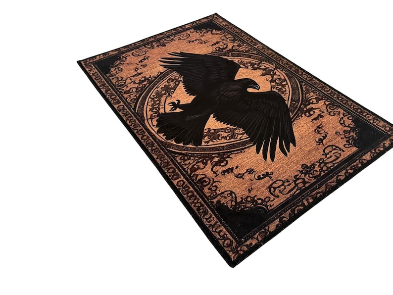 May include: Rectangular rug with a detailed black eagle design on a copper-colored background. The eagle is centered within a circular frame, surrounded by ornate patterns. The border is black, adding contrast to the overall design.