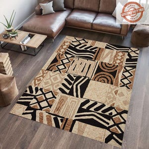 May include: A rectangular rug with a patchwork design. The rug features geometric patterns in black, beige, and brown. The rug is placed on a wooden floor, with a brown leather sofa and a wooden coffee table in the background.