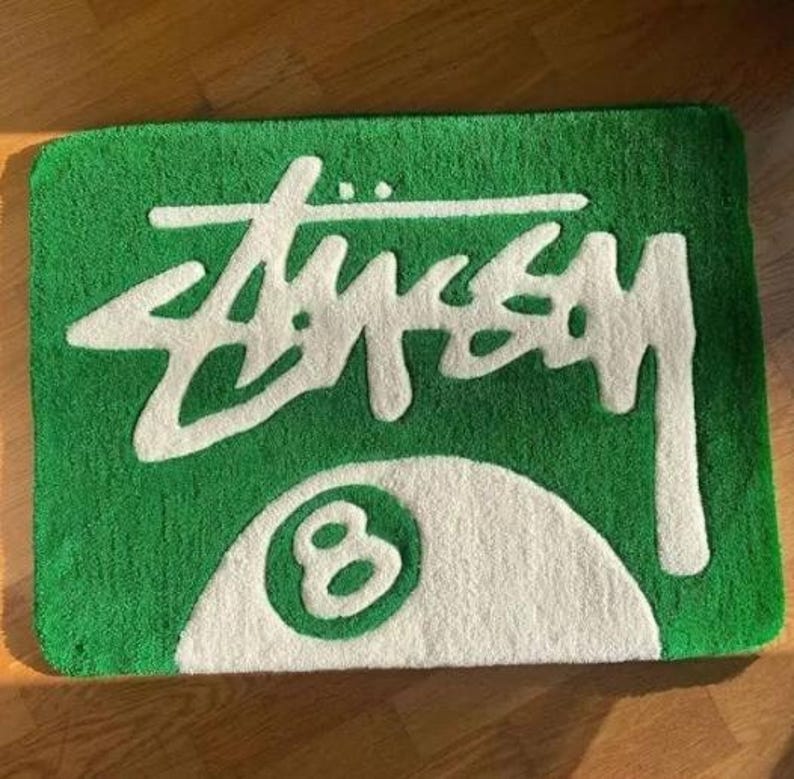 May include: Green doormat with a white 8-ball and the word "STUSSY" in white lettering.