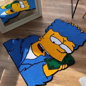 May include: A blue and yellow cartoon rug featuring a character with blue hair holding a green bill with the number 100 printed on it. The rug is made of soft, plush material.