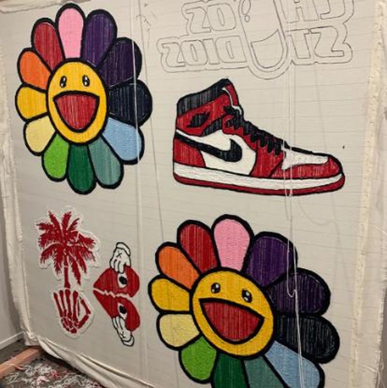 May include: A white canvas with colorful embroidered flowers, a red and white sneaker, and a palm tree with a skull and crossbones. The text "2010's" is written on the canvas.