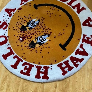 May include: A round white rug with a yellow smiley face in the center. The rug has red lettering around the edge that says "Have a Nice Day".