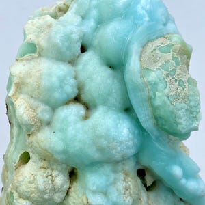 May include: A large, blue and white,  geode with a rough, textured surface. The geode has a unique, organic shape and is filled with small, white crystals.
