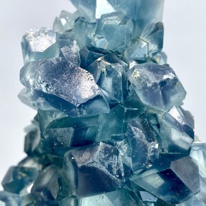 May include: A cluster of blue fluorite crystals with a glassy, translucent appearance. The crystals are arranged in a random, organic pattern, creating a visually interesting and unique piece.