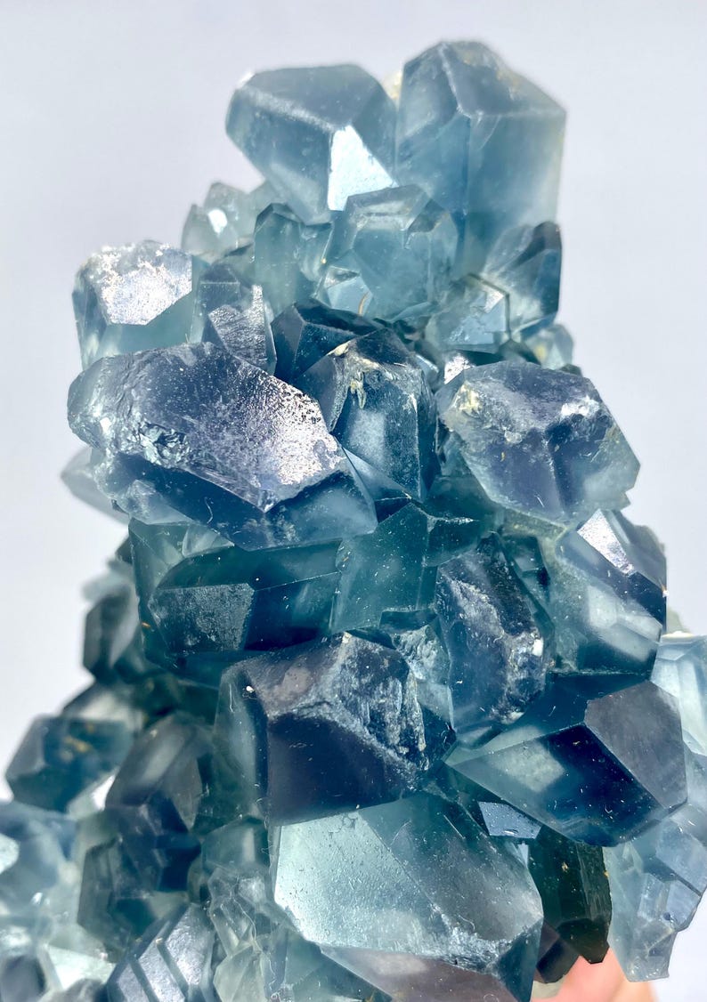 May include: A cluster of blue fluorite crystals with a glassy, translucent appearance. The crystals are arranged in a random, organic pattern, creating a visually interesting and unique piece.