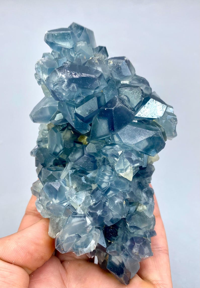 May include: A cluster of blue fluorite crystals with a glassy, translucent appearance. The crystals are arranged in a random, organic pattern, creating a visually appealing and unique piece.