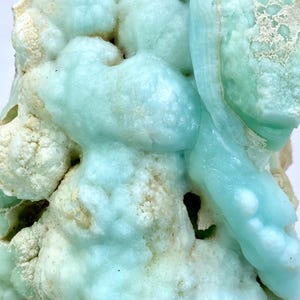 May include: A close-up of a blue and white mineral specimen with a bubbly, textured surface. The mineral has a light blue color with white accents.