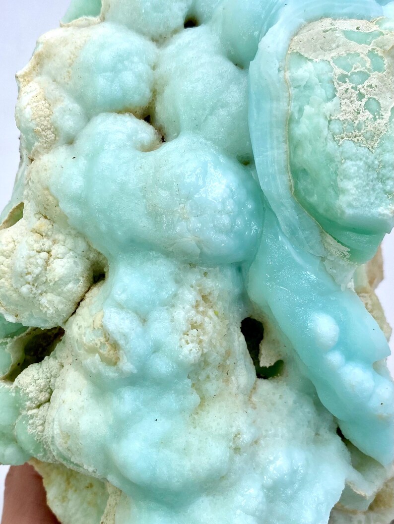 May include: A close-up of a blue and white mineral specimen with a bubbly, textured surface. The mineral has a light blue color with white accents.
