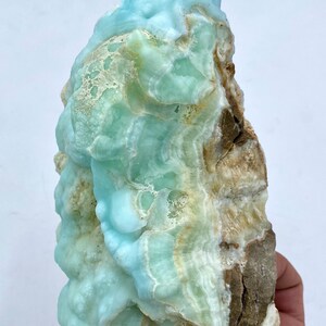 May include: A large, blue and green, naturally formed,  crystal cluster with a rough, brown exterior.