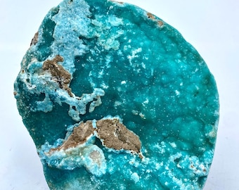 May include: A large, irregularly shaped turquoise mineral specimen with a rough, textured surface. The stone features areas of light blue and brown coloration, creating a striking contrast. The overall appearance suggests a natural, unpolished gemstone.