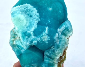 May include: A large, blue and white, crystalline mineral specimen. The mineral has a smooth, rounded surface with a few small, white inclusions.