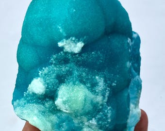 May include: A large, teal blue, mineral specimen with white and green accents. The mineral has a rough, textured surface.