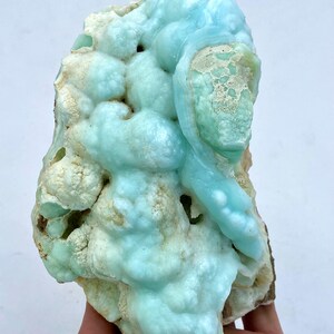 May include: A large, blue and white, geode with a unique, organic shape. The geode has a smooth, polished surface and is filled with small, white crystals.